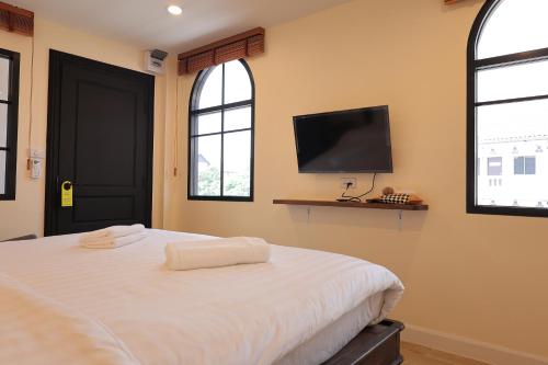 um quarto com uma cama e uma televisão de ecrã plano em Holiday Cottage Chiang Mai Old Town em Chiang Mai