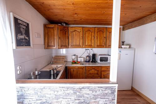 a kitchen with wooden cabinets and a white refrigerator at Coeur de Charente Maritime, la charentaise in Saint-Germain-de-Marencennes