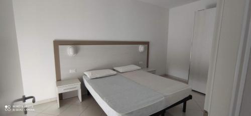 um pequeno quarto branco com uma cama e uma mesa em Residenza Acquamarina em Pinarella