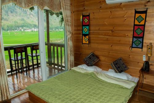 um quarto com uma cama e uma grande janela em Mai Chau La Vida Homestay em Mai Châu