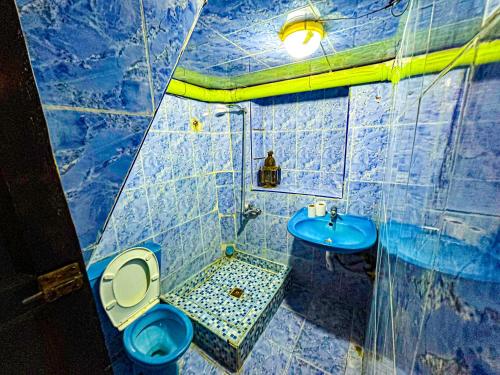 a blue tiled bathroom with a toilet and a sink at Hostel Speakeasy Fes in Fez