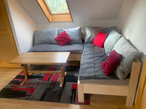 a couch with red pillows sitting next to a table at Chalupa u Desné in Petrov nad Desnou