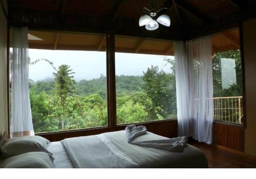 Cama en habitación con ventana grande en Finca Valle Arcoiris, en Heredia