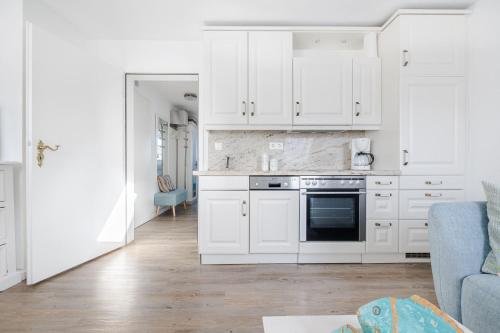 a white kitchen with white cabinets and a blue couch at Lister Wind in List