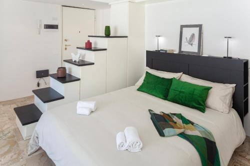 ein Schlafzimmer mit einem großen weißen Bett mit grünen Akzenten in der Unterkunft Studio ALLEGRA in Levanto