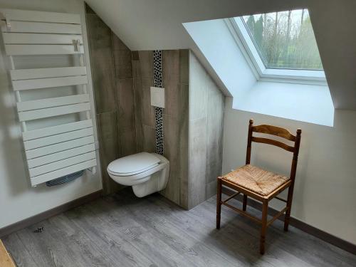 La salle de bains est pourvue de toilettes et d'une chaise. dans l'établissement Maison terre et bord de mer, à Lessay