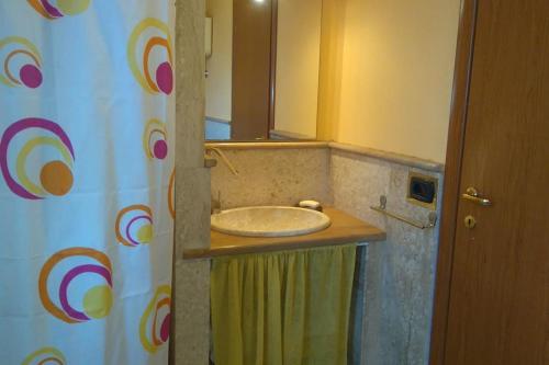 a bathroom with a sink and a shower curtain at Open Space da Luca e Laura,a 7 minuti da Alghero. in Olmedo