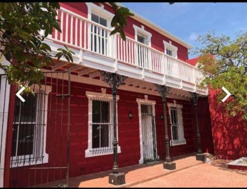 uma casa vermelha com uma varanda branca por cima em Jerusalem Backpackers em Cidade do Cabo