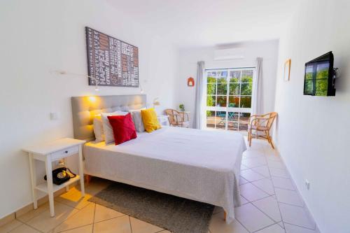 a bedroom with a bed and a table and a window at Casas Novas Guesthouse - Adults Only in Lagos