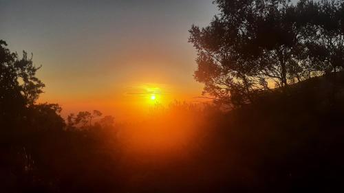 a sunset with the sun setting in the sky at Bungalow Tillandsia in Le Tampon