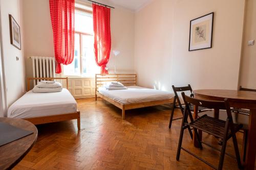 a room with two beds and a table and a table at Trzy Kafki Private Rooms in Kraków