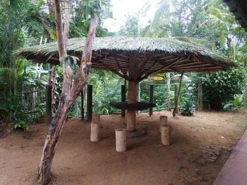 a straw hut with a table in a forest at VIMAANAYA Cabana & Restaurant in Badulla