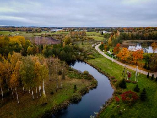 une vue aérienne sur une rivière arborée et une route dans l'établissement Meiranu krasts, à Bērzgale