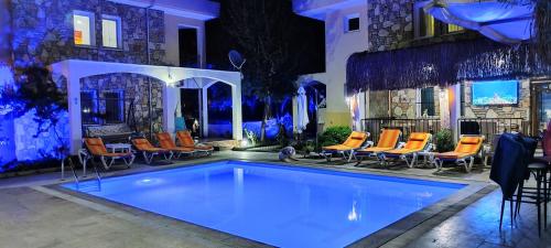 una piscina con sillas naranjas y un edificio en çileks apart otel, en Fethiye