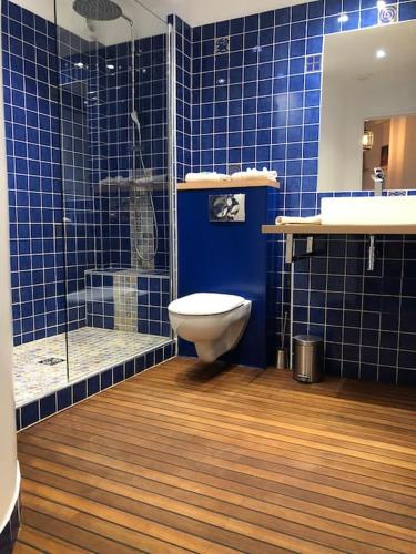 La salle de bains est pourvue de carrelage bleu, de toilettes et d'une douche. dans l'établissement Paris Bois de Vincennes Appartement 50 m2, à Vincennes