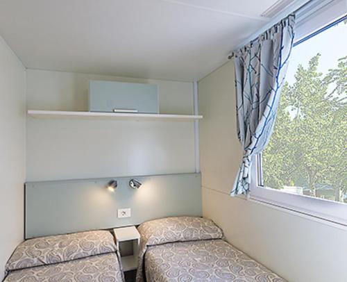 mały pokój z 2 łóżkami i oknem w obiekcie EUROCAMPINGPACENGO w mieście Pacengo di Lazise