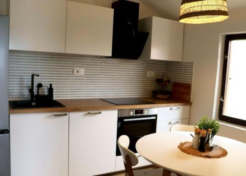uma cozinha com armários brancos e uma mesa e uma mesa e cadeiras em Sol Insula em Murter