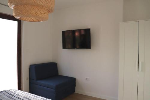 um quarto com uma cadeira azul e uma televisão na parede em Sol Insula em Murter
