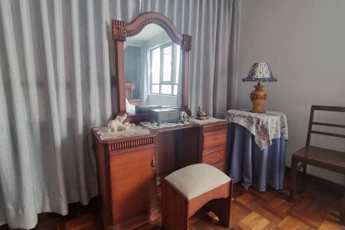 eine Holzkommode mit einem Spiegel und einem Stuhl in der Unterkunft Central and quiet apartment in Cochabamba in Cochabamba