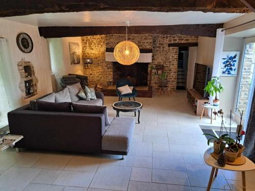 a living room with a couch and a brick wall at Un petit coin de paradis près de Rennes in Tresboeuf
