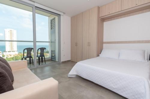a bedroom with a white bed and a large window at Beachside Bliss: Salguero Suites in Gaira