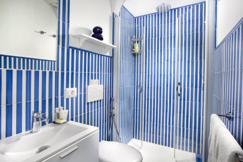 La salle de bains est pourvue de carrelage bleu, de toilettes et d'un lavabo. dans l'établissement Casa Mimosa, à Positano