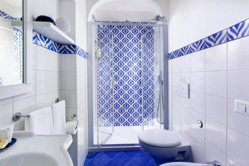 a blue and white bathroom with a toilet and a shower at Casa Mimosa in Positano