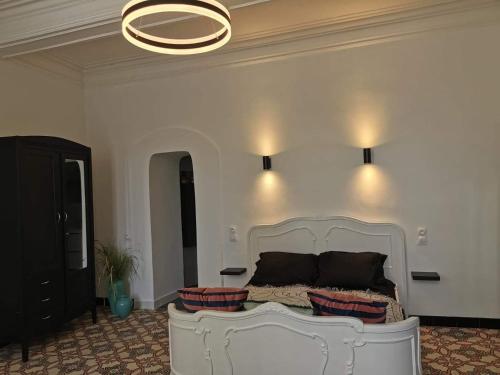 - une chambre avec un lit blanc et un lustre dans l'établissement Maison de village avec sa charmante grand chambre avec balcon, à Fleury