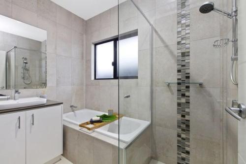 a bathroom with a shower and a tub and a sink at Private Room in Palmerston in Palmerston