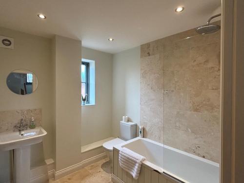 a bathroom with a tub and a toilet and a sink at Rookery Cottage in Mundesley