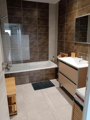 une salle de bain avec une baignoire et un lavabo dans l'établissement Colombiers Escale à la Noria Appartement terrasse 4 personnes et garage, à Colombiers