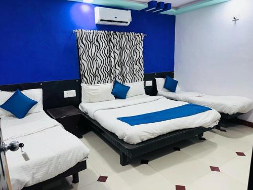 a room with three beds and a blue wall at HOTEL SHREE DWARKA in Dwarka