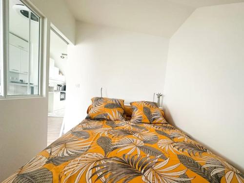 a bed in a bedroom with an orange and brown blanket at Charmant studio proche de la gare in Rambouillet