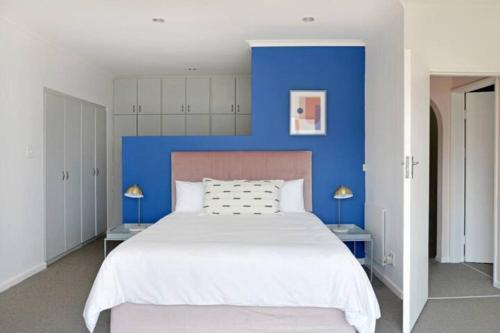 1 dormitorio con 1 cama grande y pared azul en The Bakoven Rock, en Ciudad del Cabo