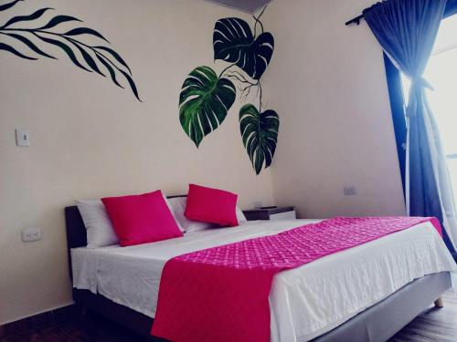 a bedroom with a bed with pink and green pillows at Best View Aparta Hotel in Dosquebradas