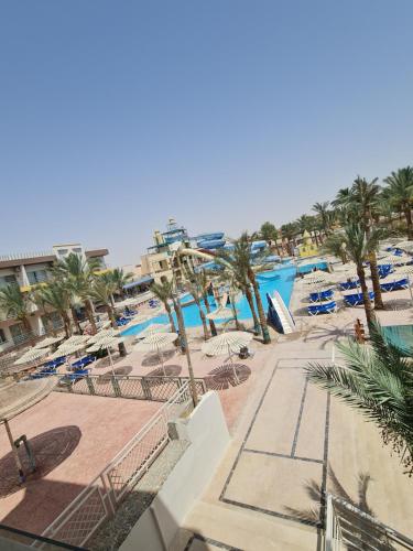 a resort with a pool with chairs and palm trees at ميراج باي (شاليه) in Hurghada