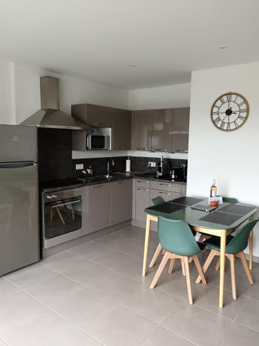 une cuisine avec une table, des chaises et une horloge dans l'établissement Colombiers Escale à la Noria Appartement terrasse 4 personnes et garage, à Colombiers