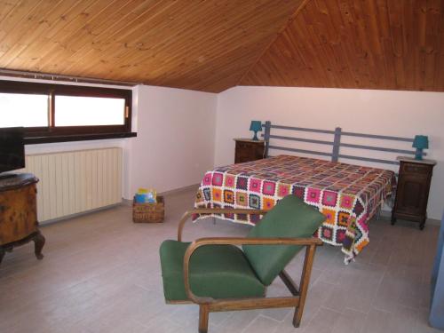 a bedroom with a bed and a green chair at Villa Formica - Vista su Castello di Gradara in Gradara