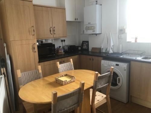 a kitchen with a wooden table and a table and a dishwasher at Butterfly Home in London