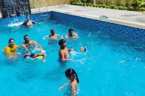 a group of people playing in a swimming pool at Aarul Farms in Gurgaon