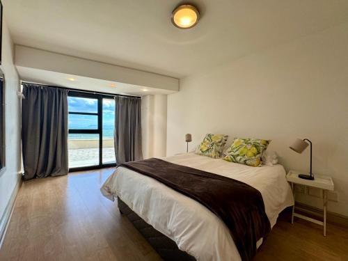 a bedroom with a bed and a large window at Loddey's Self Catering Apartments in Strand