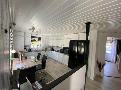 Husum的住宿－Nordic Villa，厨房配有白色橱柜、桌子和冰箱。