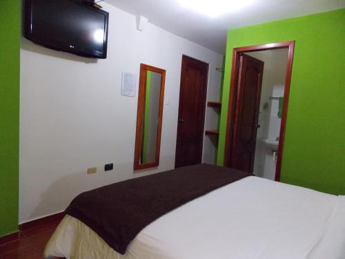 a bedroom with green and white walls and a bed at Green House Araque Inn in Otavalo
