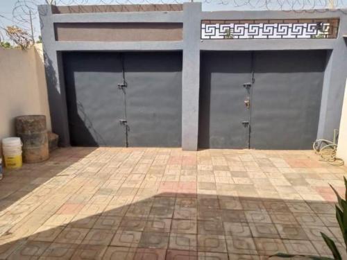 2 puertas de garaje en un edificio con suelo de baldosa en RESIDENCE OUAGA, en Ouagadougou