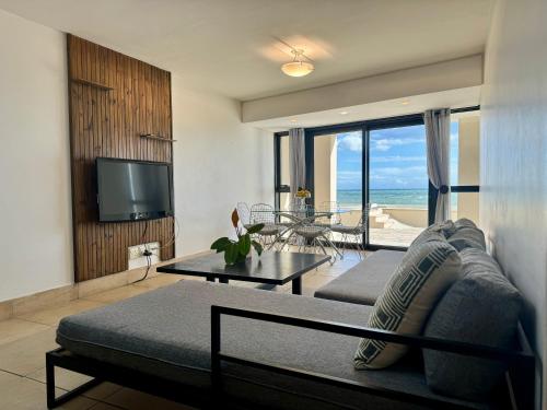 een woonkamer met een bank, een tv en een tafel bij Loddey's Self Catering Apartments - by Beach Collection in Strand