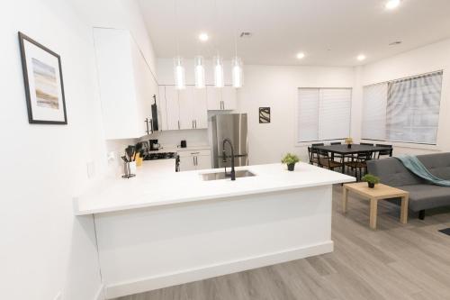 eine weiße Küche und ein Wohnzimmer mit einem Sofa in der Unterkunft Mins to NYC - Lavish modern 2-bed apartment in Bayonne