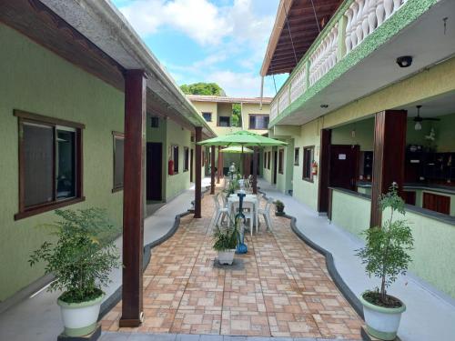 un patio con mesas y una sombrilla en un edificio en Pousada Sol e Lua en Caraguatatuba
