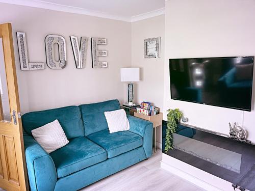 a living room with a blue couch and a flat screen tv at The Serene Stays Sleeps 6 with Garden in Oldham
