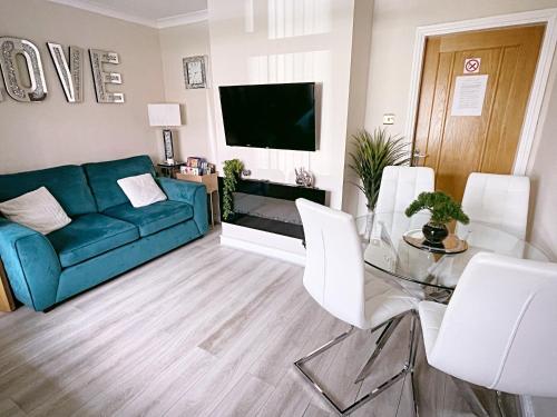 a living room with a blue couch and a glass table at The Serene Stays Sleeps 6 with Garden in Oldham