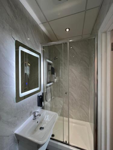 La salle de bains est pourvue d'un lavabo et d'une douche. dans l'établissement Boutique Apartments, à Londres